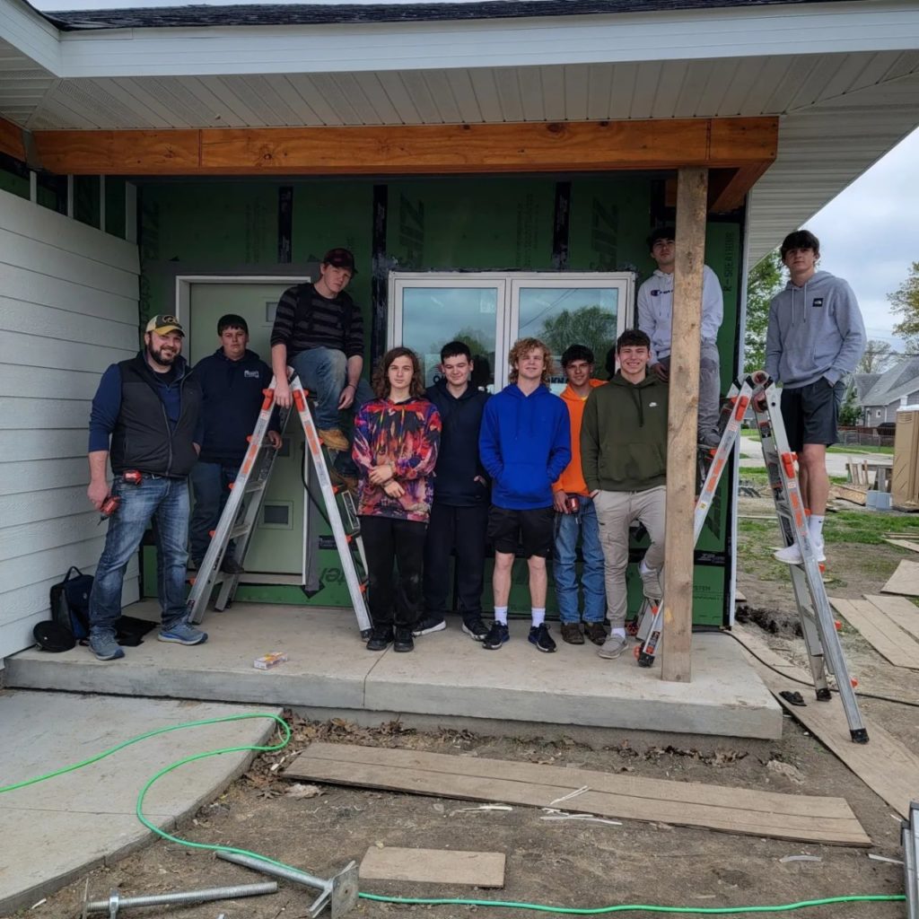 Students from the Taylorville High School Building Trades Program adding siding to the house they're building as part of this course.